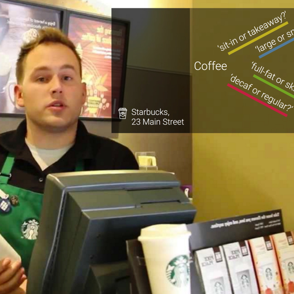 A starbucks employee is shown behind the counter. To the top right of the frame is a glancable text display showing some common phrases spoken inside a coffee shop.