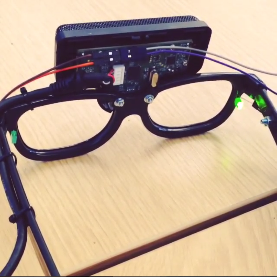 An image of a microphone array mounted on a pair of eyeglasses, with LEDs at the left and right